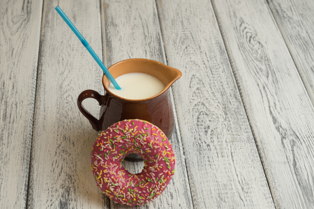 Donut with icing on white wooden background with milk jugの写真素材