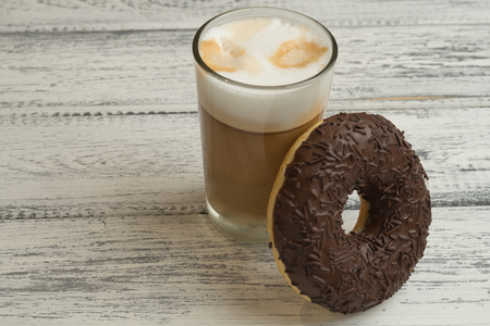 Donuts with frosting and cappuccino on white wooden backgroundの写真素材