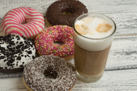 Donuts with frosting and cappuccino on white wooden backgroundの写真素材