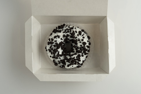 Chocolate donut with icing in a box, isolated on white backgroundの写真素材