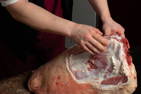 Close-up of the hands of a butcher cutting slices of raw lambの写真素材