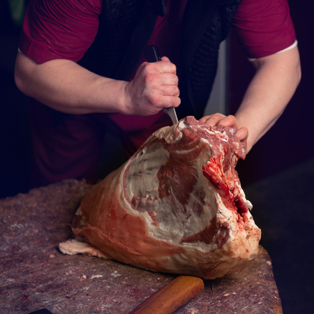 Close-up of the hands of a butcher cutting slices of raw lambの写真素材