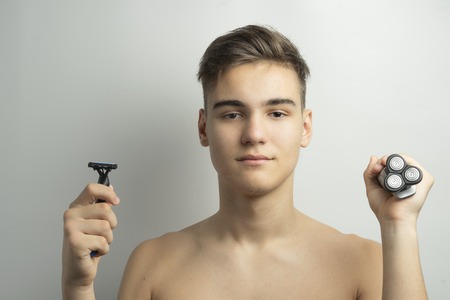 A teenager is choosing between a razor and an electric shaverの写真素材