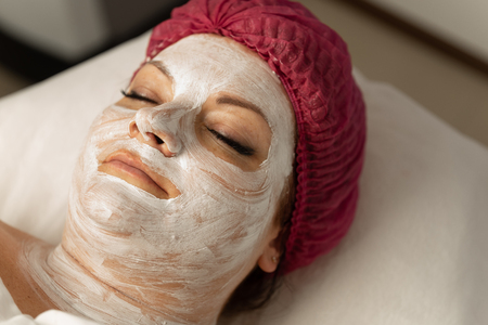 Spa concept. Young woman with nourishing mask on face relaxing in spa salonの写真素材