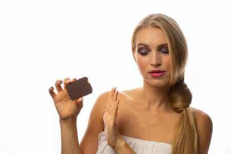 Young woman eating chocolate cookie ,with shame for mistake. Over isolated backgroundの写真素材