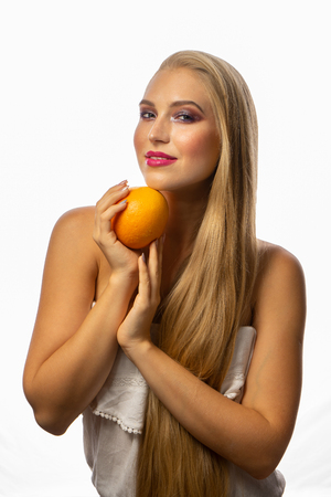 Beautiful sexy young woman with perfect healthy skin and long blonde hair holds orange grapefruitの写真素材