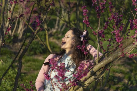 Spring Beautiful romantic girl is standing in blooming gardenの写真素材