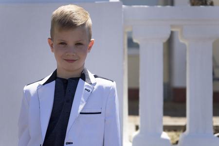 Children's fashion and style. A handsome boy, fashion model in elegant white jacket is posing for cameraの写真素材