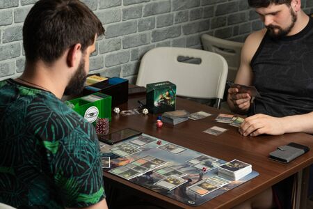 SOCHI, RUSSIA-MAY 17, 2019: Two bearded hipsters are playing a new part of the board game The War of the Spark Magic The Gathering liesのeditorial素材