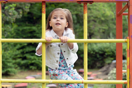 Little blonde girl of three to four years old are playing on the Playground, she is climbing on...