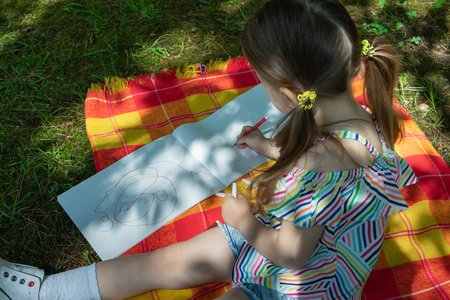 kid little girl is drawing with felt-tip pen in the parkの写真素材