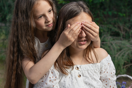 Warm family relations between mother and daughter. Girl is closing her mother eyes in the park.の写真素材