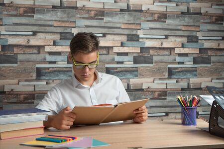 Pupil in glasses reading a book, doing homework. Concept of back to schoolの写真素材