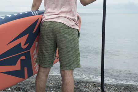 Man standing with surfboard at sunset stand up paddle boardingの写真素材