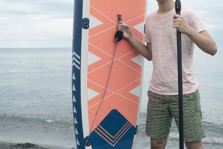 Young surfer with a SUP board Stand up paddle boarding on the seacoastの写真素材