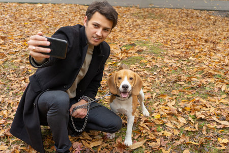 A young guy takes a selfie with his dog. Stylish man and his Beagle outdoor. Pet
