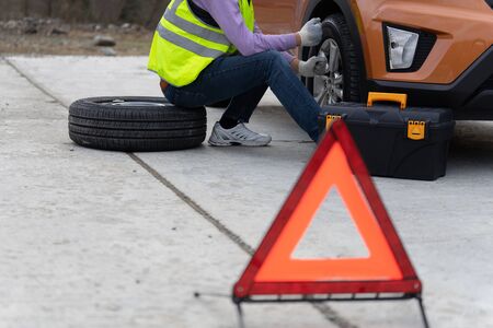 Emergency roadside assistance, technician helps with wheel replacement.の写真素材