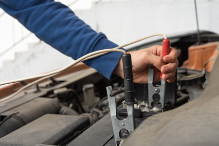 A mechanic using jumper cables to start a car battery.