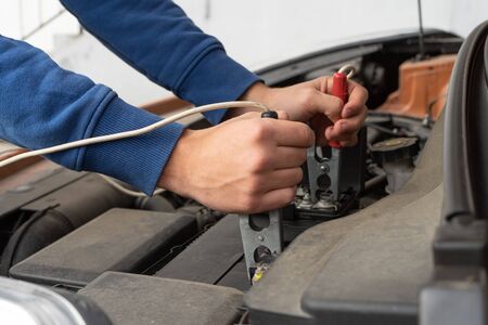 Closeup of the hands of a mechanic using jumper cables to start a carの写真素材