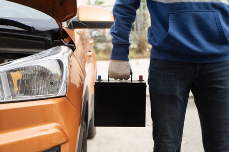The buyer keeps the new black car battery next to the vehicleの写真素材