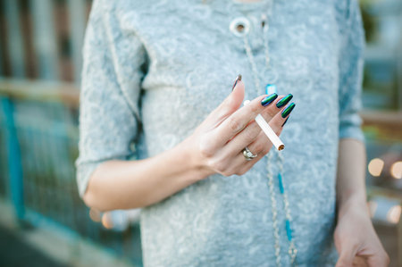 girl with a cigarette. young beautiful woman smokes a cigarette in the streetの写真素材