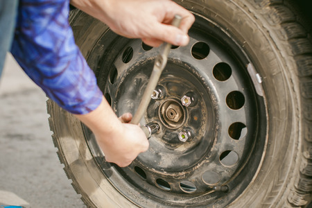 man changing a wheel on the road. on way there was breakage of wheel, puncture, necessary to lift the car jack and remove the wheel by loosening the nuts. road problems travelers. do it yourselfの写真素材