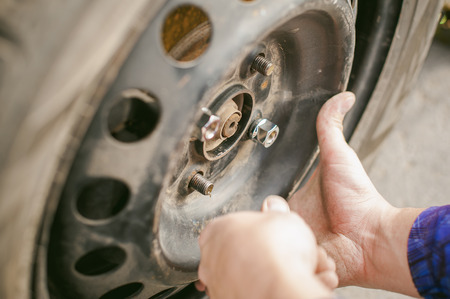 man changing a wheel on the road. on way there was breakage of wheel, puncture, necessary to lift the car jack and remove the wheel by loosening the nuts. road problems travelers. do it yourselfの写真素材