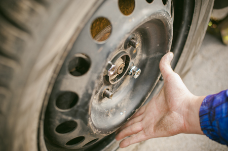 man changing a wheel on the road. on way there was breakage of wheel, puncture, necessary to lift the car jack and remove the wheel by loosening the nuts. road problems travelers. do it yourselfの写真素材