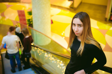 young woman in a black dress goes on the escalator at the mallの写真素材