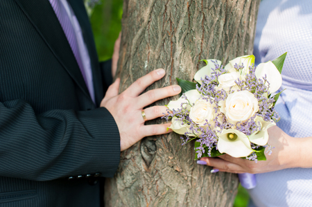 bridal bouquet and newlyweds rings. hands adult honeymooners close upの写真素材