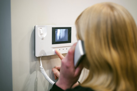 blonde woman answers the intercom call while holding the phone to your earの写真素材