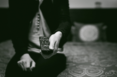 girl in a home environment, holding a TV remote, switching channelsの写真素材