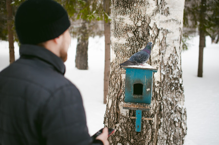 a young man with a beard, smokes an electronic cigarette and happily talking on the phone through the Internet, a positive relaxing outdoors in the snow in the winterの写真素材