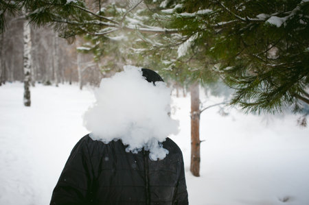 a young man with a beard, smokes an electronic cigarette, outdoors in winter snowの写真素材