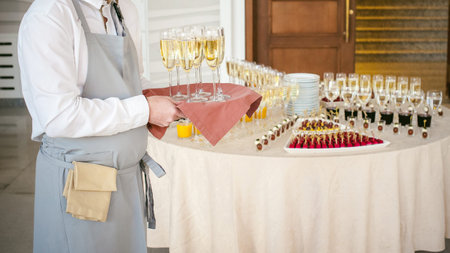 waiter with a tray of champagne in hand on background fourchette table