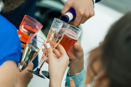 Champagne is poured into plastic glasses guestsの写真素材