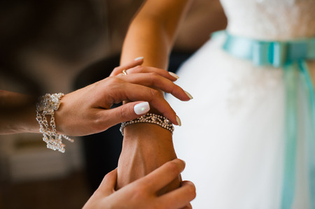 girl straightens his hands bracelet jewelry on the bride's wrist. bridesmaid helps the bride's feesの写真素材