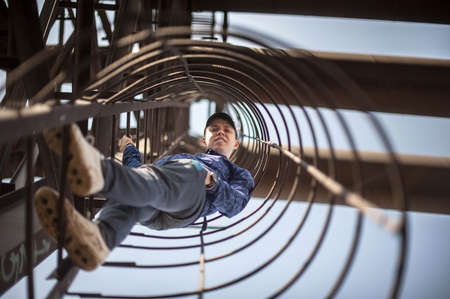 young attractive guy rises up the steps of a rusty metal staircase, wearing a cap and a sports jacket.の写真素材