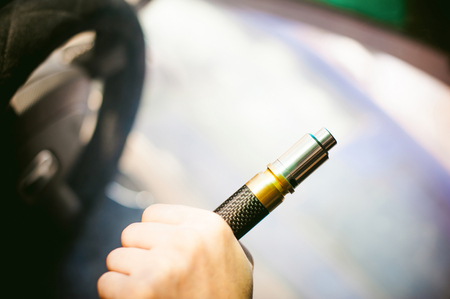 young vaper man with beard vaping mechanical mod. Guy smokes an electronic cigarette by blowing a smoke vapor. Holds in hand on colorful backgroundの写真素材