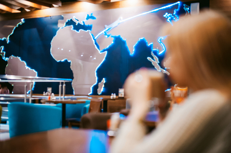 Cute young blonde woman drinks hot coffee from a glass cup in the interior of a coffee house. Abstract blur, out of focusの写真素材