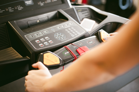 young woman is engaged fitness in gym. Performs cardio load on treadmill, running and walking with acceleration. sport, fit, lifestyle, technology and people conceptの写真素材