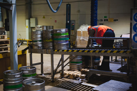 Process of transfer of aluminum kegs from filling line to pallet, employee of production line at...