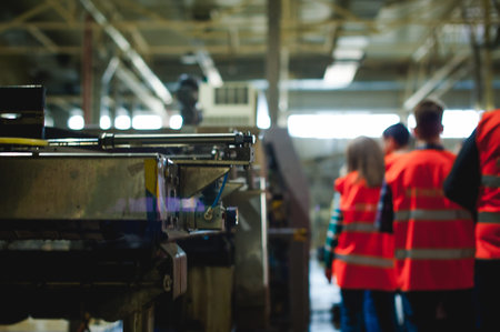 blonde woman in overalls, on the tour of the brewery plant in industrial premises, amid crowds of...