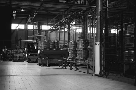 Warehouse employee in Overalls clothes, driver Reachtruck busy working on logistics Moving on loader pallets with beer kegs on line of factory for production of beer. human labor in manufacturingの写真素材