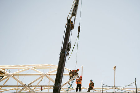 man in overalls  builder fixes on the height. Assembling, refurbishment works at altitude with metal...