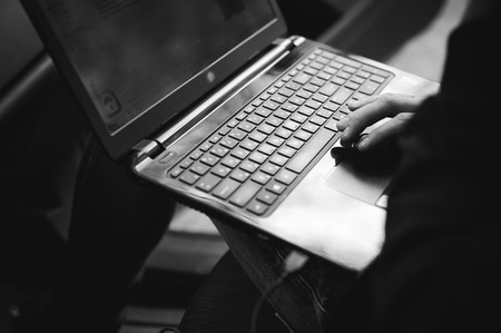 Professional man with a laptop in car tunes tuning control system, updating software, gaining access through to computer, sitting in cabinの写真素材