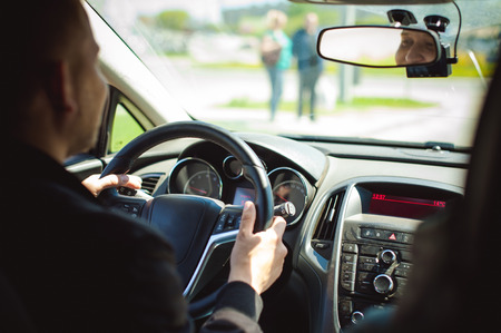 young bearded man driving a car, inside cabin rides, looking at road, driving, holding steering wheel.の写真素材