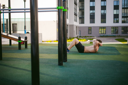 Handsome sexy male bodybuilder athlete man with naked torso Lies on the ground in courtyard. Healthy...