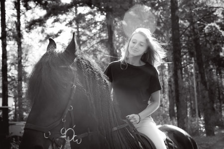Emotional portrait of a horsewoman rider woman, astride, in love with horses, black Friesian...