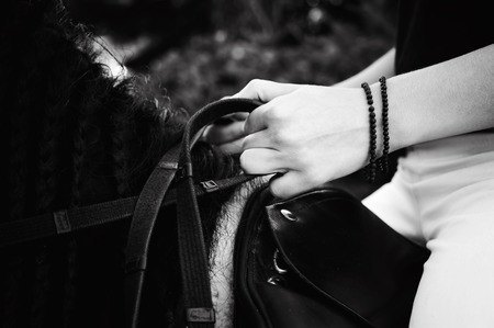 Emotional portrait of a horsewoman rider woman, astride, in love with horses, black Friesian stallion thoroughbred pet, outdoorsの写真素材